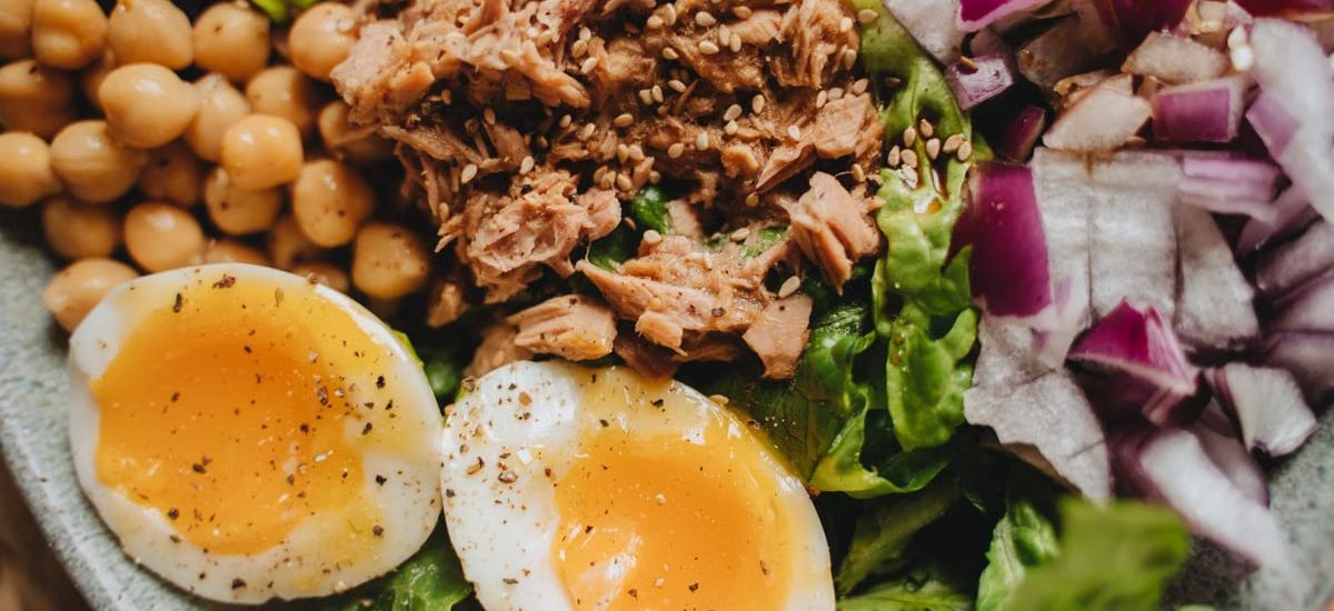 Close-up of a nutritious salad with tuna, soft-boiled eggs, and fresh vegetables.