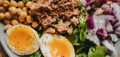 Close-up of a nutritious salad with tuna, soft-boiled eggs, and fresh vegetables.