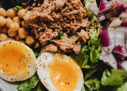 Close-up of a nutritious salad with tuna, soft-boiled eggs, and fresh vegetables.